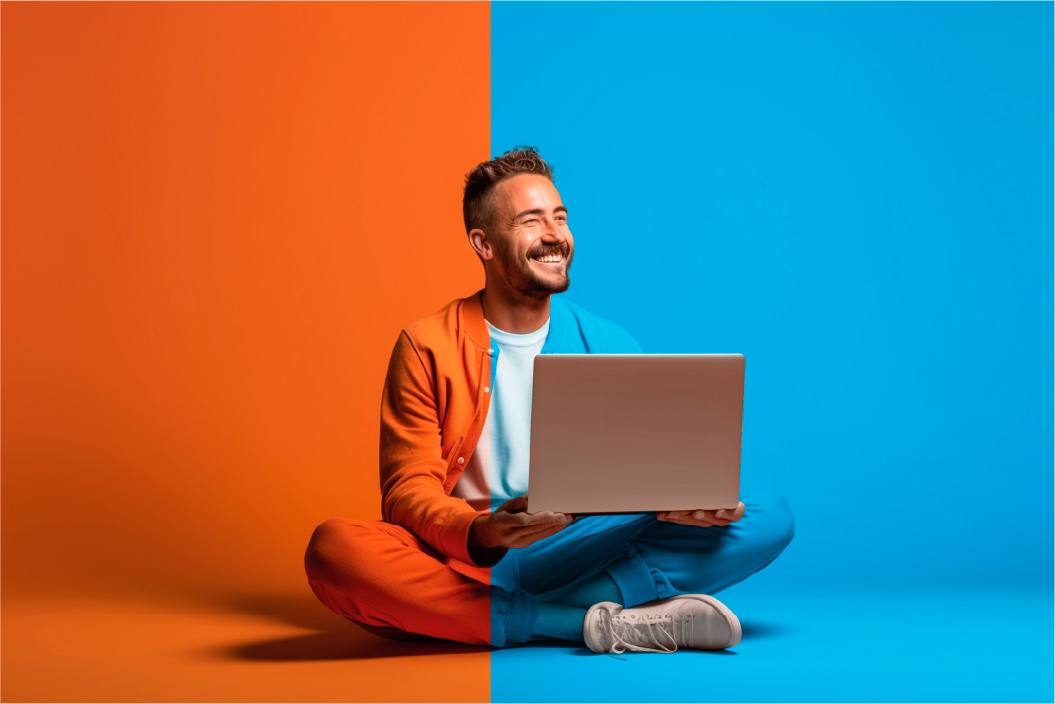 Smiling professional sitting with a laptop against an orange and blue background